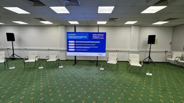 Зал форума целиком: LED-экран на стойке и ряды кресел перед сессией