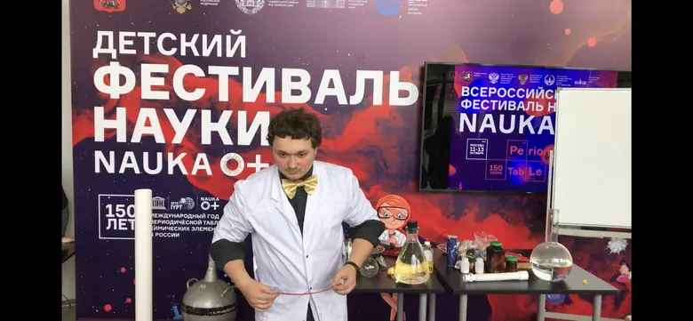 Ведущий за столом с оборудованием на сцене фестиваля