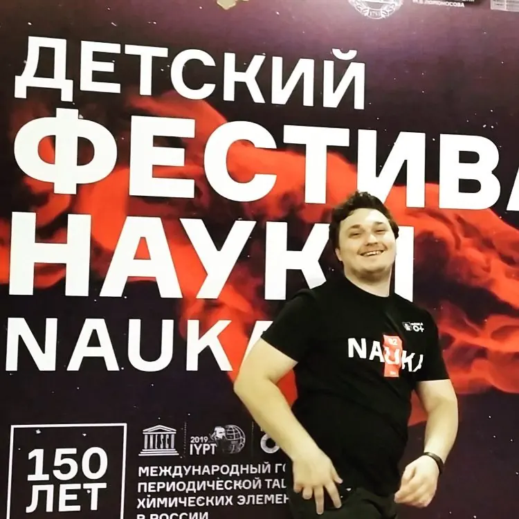 Владислав Саенко в футболке NAUKA у баннера Детского фестиваля науки